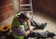 A man sitting on the ground in front of a brick wall.