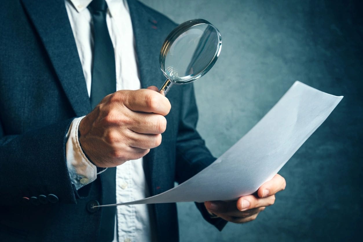 A man holding a magnifying glass and paper.