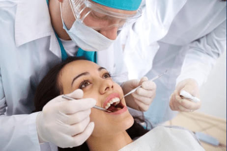 A woman getting her teeth checked by an dentist.